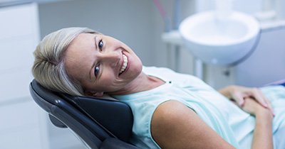 Woman leaning back in dental chair and smiling