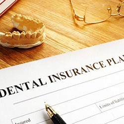 Dental insurance form on desk next to model of teeth