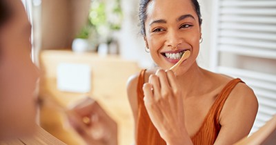 Woman smiling while brushing her teeth